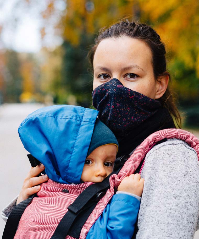 A working mother with a facemask and her very young child.